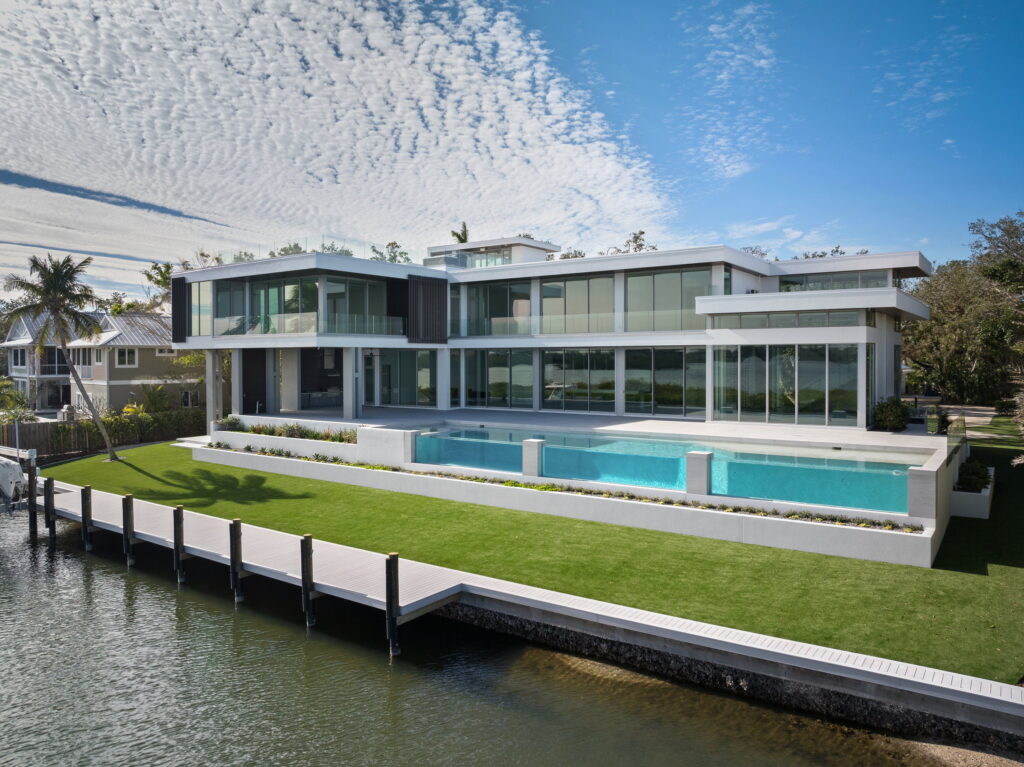 Blackfin waterfront residence with a modern rear facade, pool, lawn, and private dock